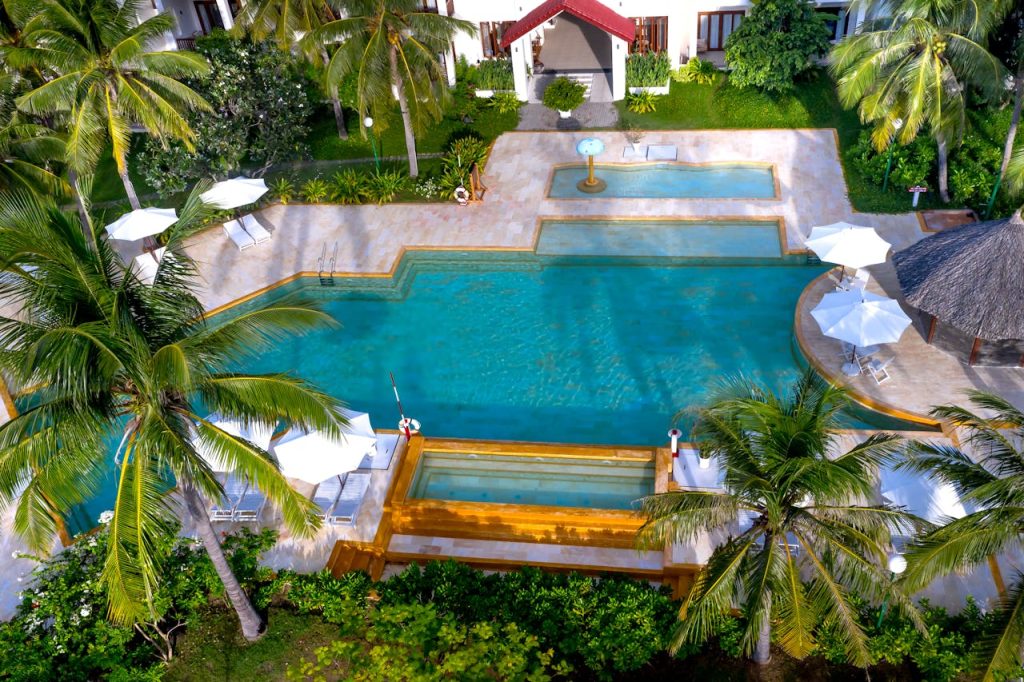 Aerial view of a luxurious tropical resort with swimming pool and palm trees.